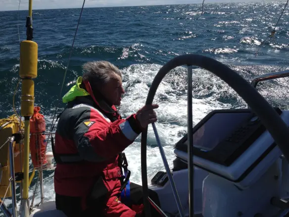 Yacht under sail along coastline during RYA Coastal Skipper training
