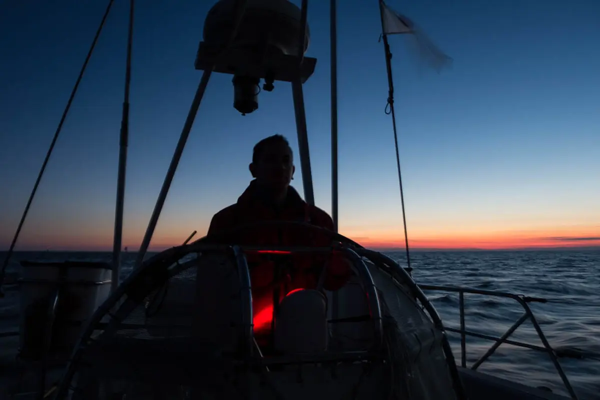 Crew Steering yacht by compass under starry Atlantic sky at night